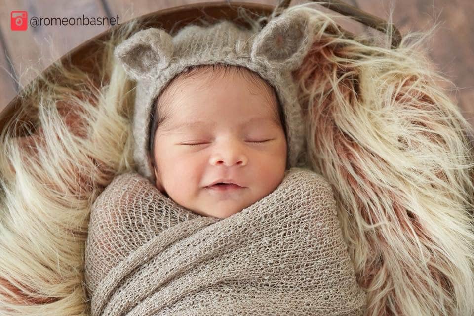 newborn baby smiling while asleep in bassinet