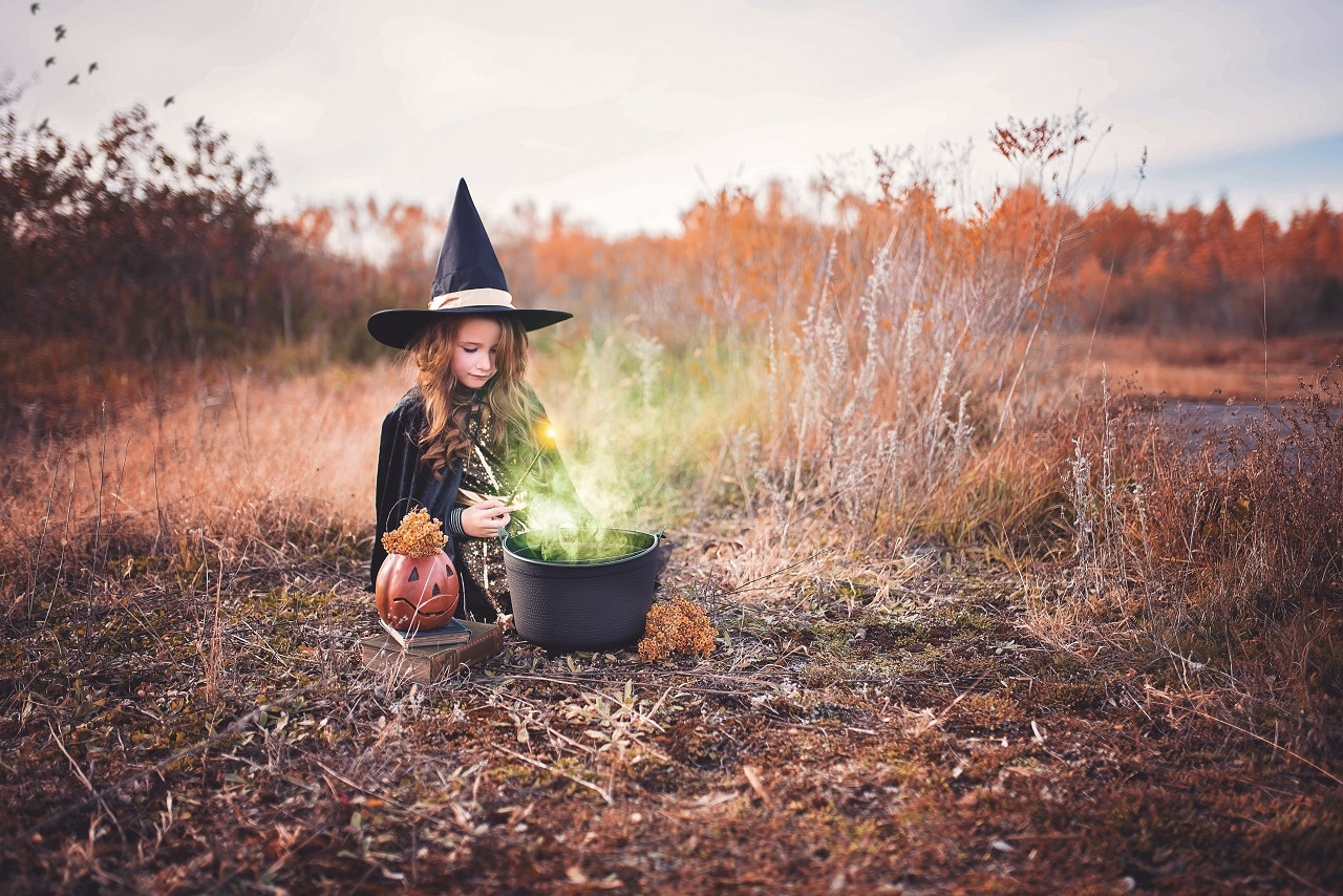 Child wearing a friendly witch costume outdoors in autumn