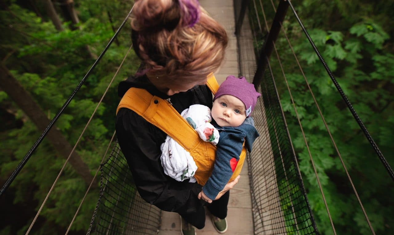 woman carrying baby on a bridge