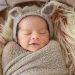 newborn baby smiling while asleep in bassinet